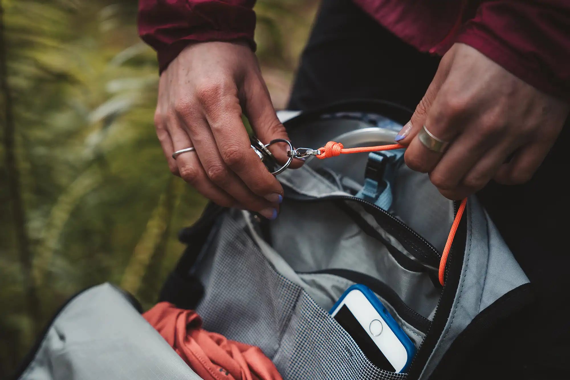 Close up of person attaching keys to key clip inside High Above Supernatural Hydration Vest Pack