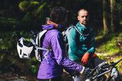 Two mountain bikers wearing High Above Supernatural Hydration Vest Pack with full face helmets attached.