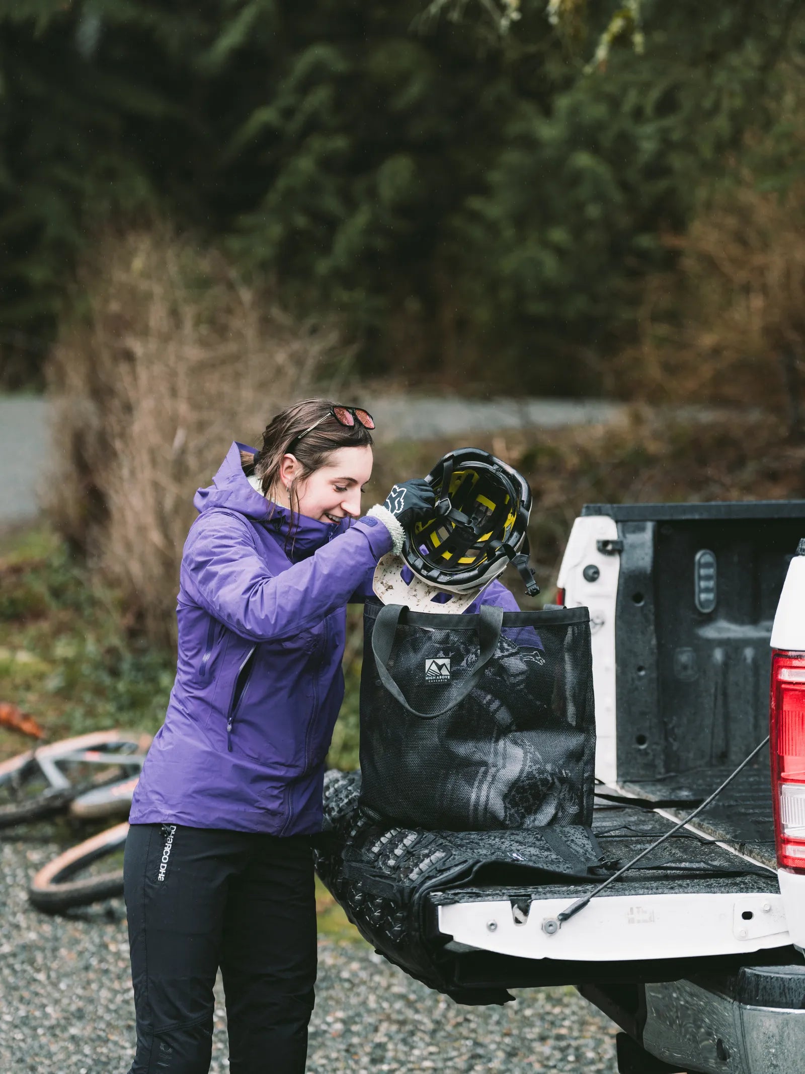 Woman loading mountain bike helmet into High Above Lost Lake Tote Bag