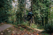 Mountain biker hitting jump while wearing High Above Lookout Hip Pack