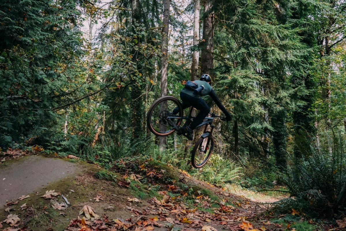 Mountain biker hitting jump while wearing High Above Lookout Hip Pack