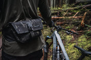 Person wearing High Above Venture hip pack with mountain bike in the forest