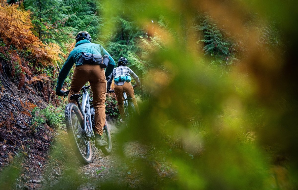 Two mountain bike riders wearing high above venture hip packs riding through forest