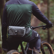 Person riding a bike with a High Above Venture 3D hip pack in a forest setting